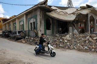 A young man rides a moped past a mosque that was targeted in an Israeli strike in the southern Lebanese village of Kfar Sir on April 21, 2026